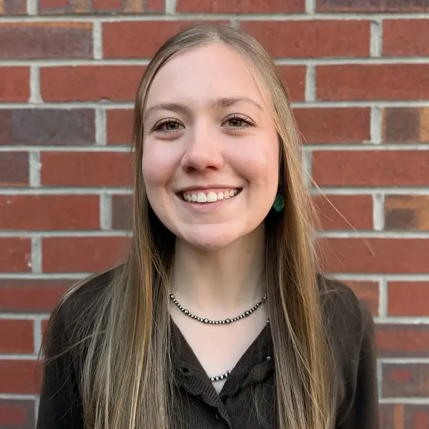 Portrait of a woman with long hair in front of a brick wall