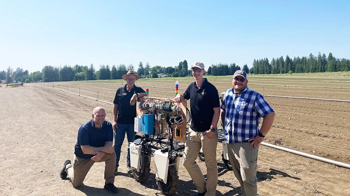 (Left to right) University of Idaho student Brent Knopp, professor John Shovic and students Garrett Wells and Kevin Wing stand with their autonomous wheeled robot that uses AI to detect and eradicate weeds. The project is in partnership with the U.S. Department of Agriculture to improve national reforestation efforts.A team from the University of Idaho robotics program recently built a wheeled robot that uses electricity to kill weeds in US Forest Service nursery seedling beds in Coeur d'Alene, ID. The robot travels rows via a programmed route while following data to differentiate between seedlings and weeds. It uses a moveable arm and electricity to “zap” weeds, killing them with a more than 95% efficiency, reducing labor costs and the use of petrol chemicals.