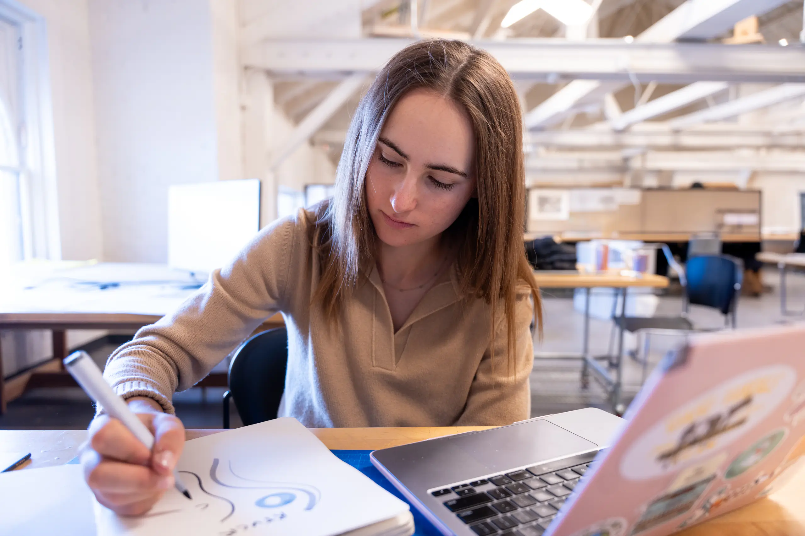 Jenna Bruggeman writes on a stack of papers with a marker, with a laptop computer nearby.