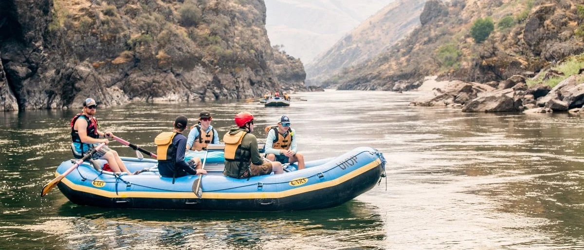 5 students rafting on a rocky river