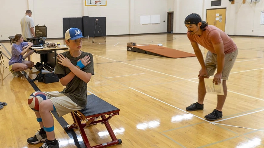 Young boy performing a core stretch in gymnasium.