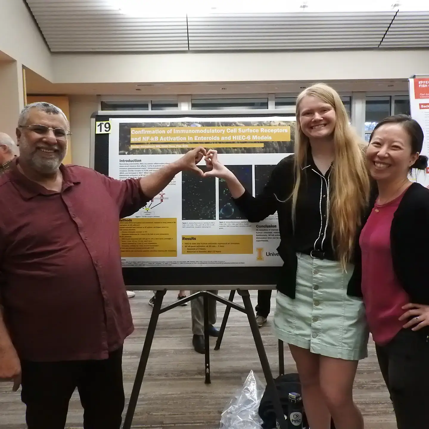 Three individuals standing in front of a poster board.
