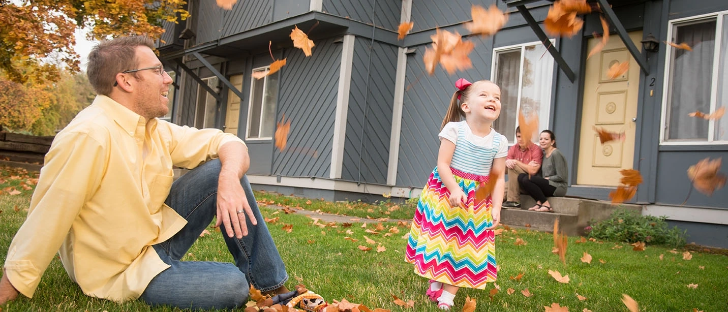 Parent and child play with leaves in autumn