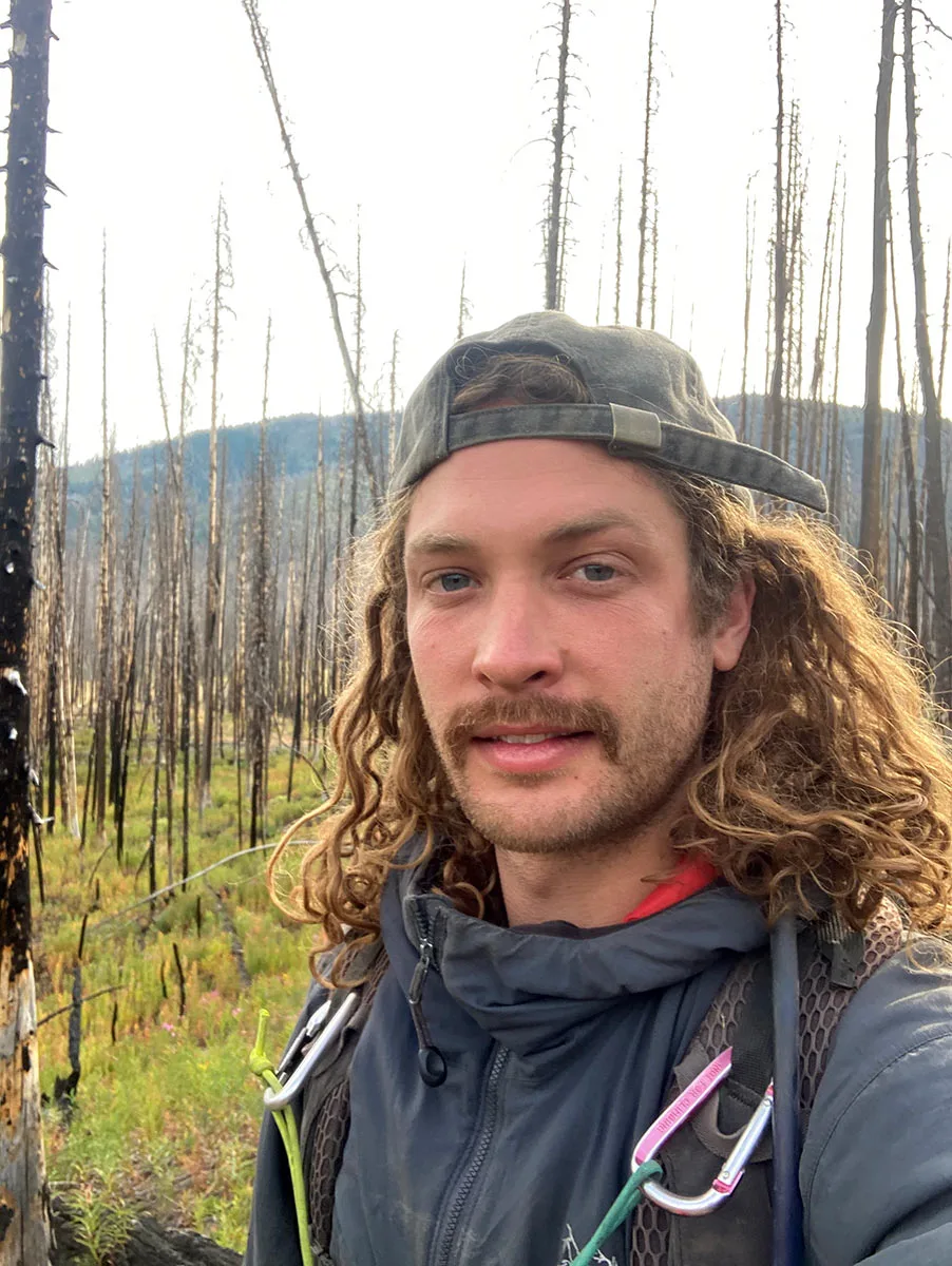 Peter Rebholz stands in a recently burned forest.