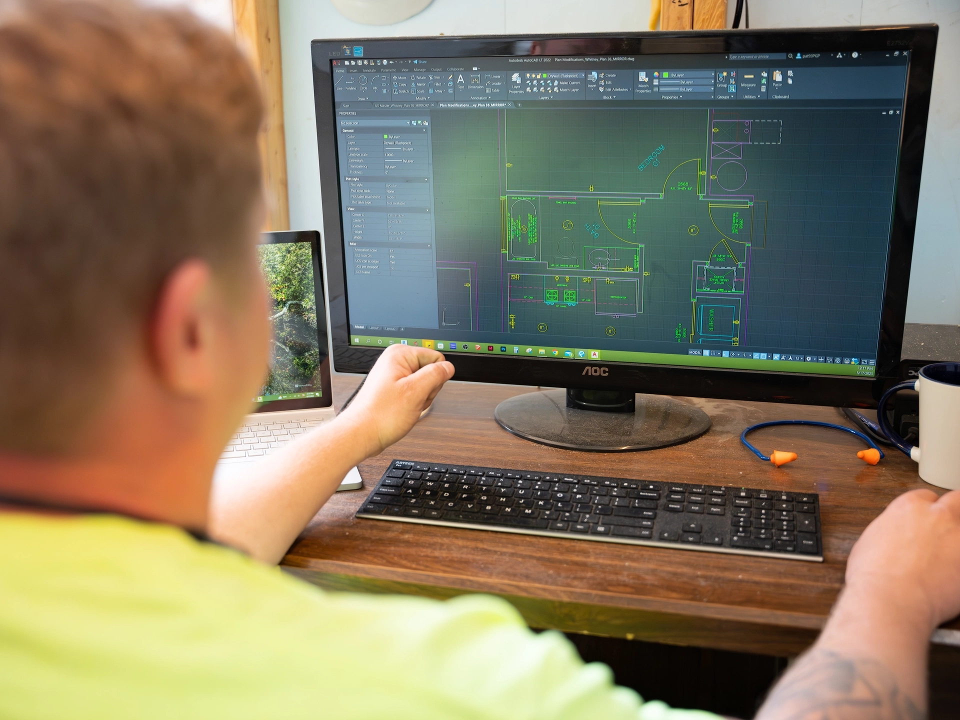 Person sitting at computer, monitor showing floorplan of a house