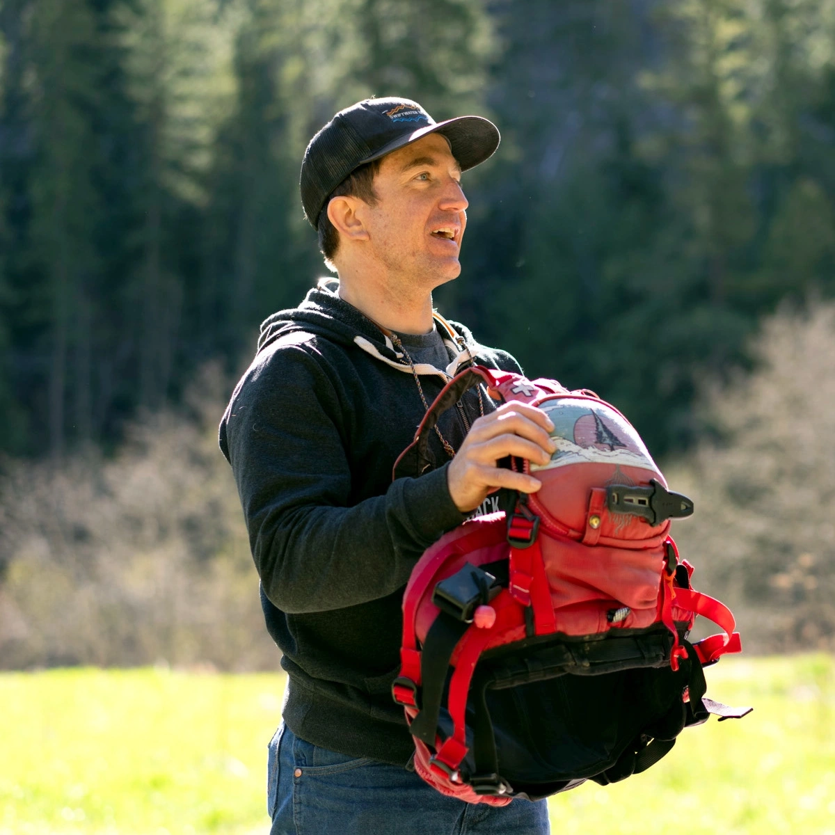 A man opening his red backpack outside