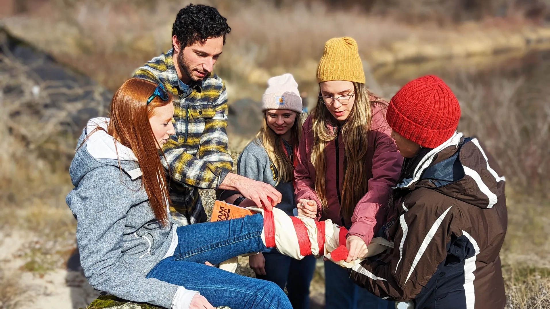Idaho WWAMI students tie a leg brace around a volunteer victim during a medical simulation