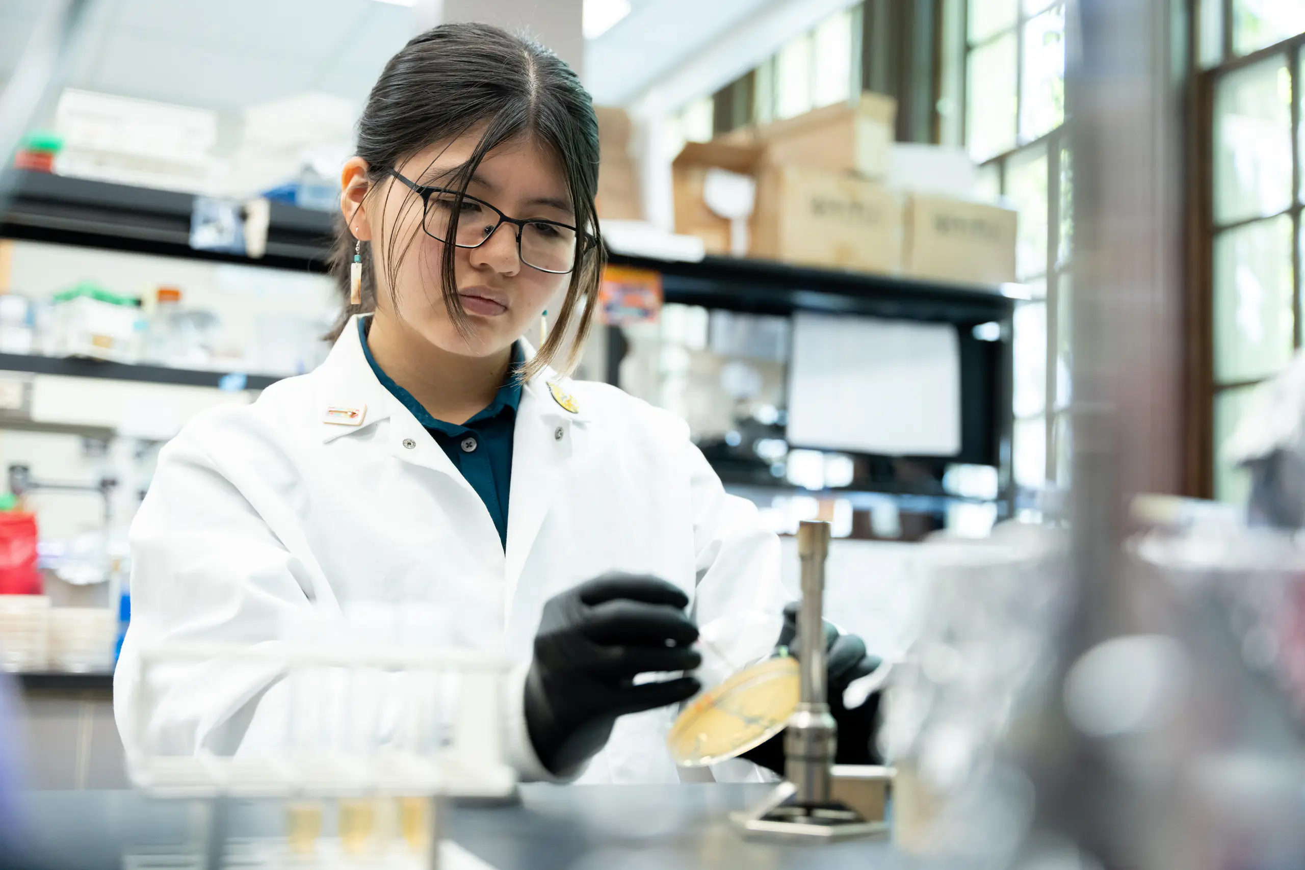 A woman in a lab coat holding a petri dish