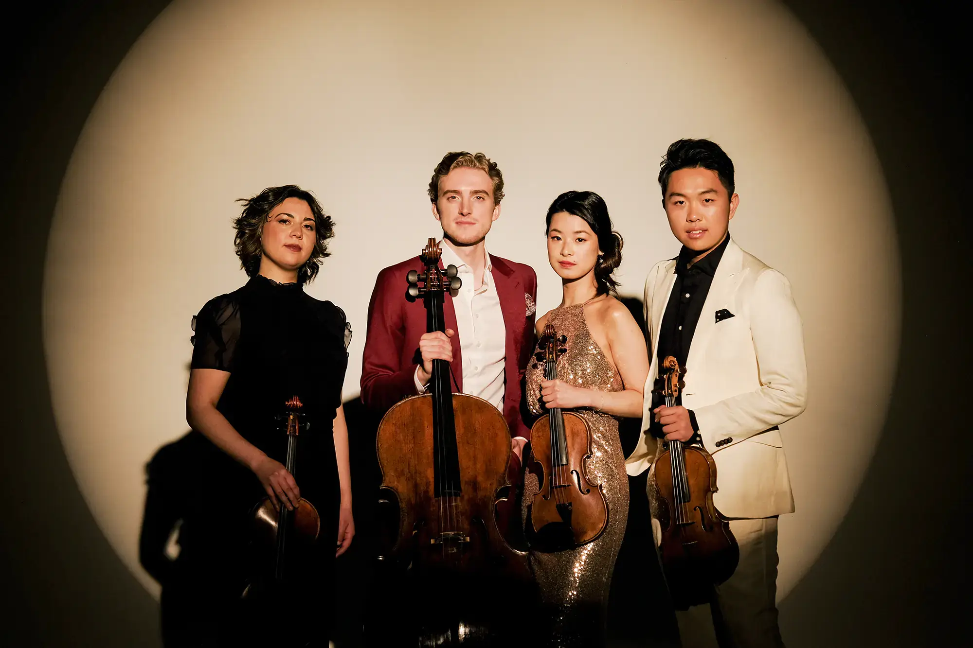 Group photo of three violinists and a cellist with their instruments.