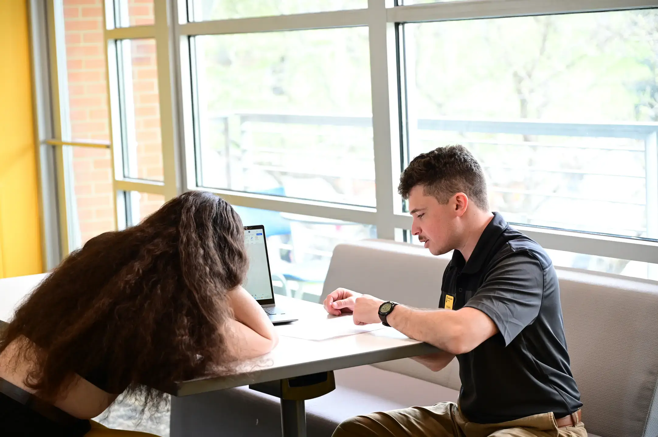Two people sit at a table in the ISUB and work on a laptop.