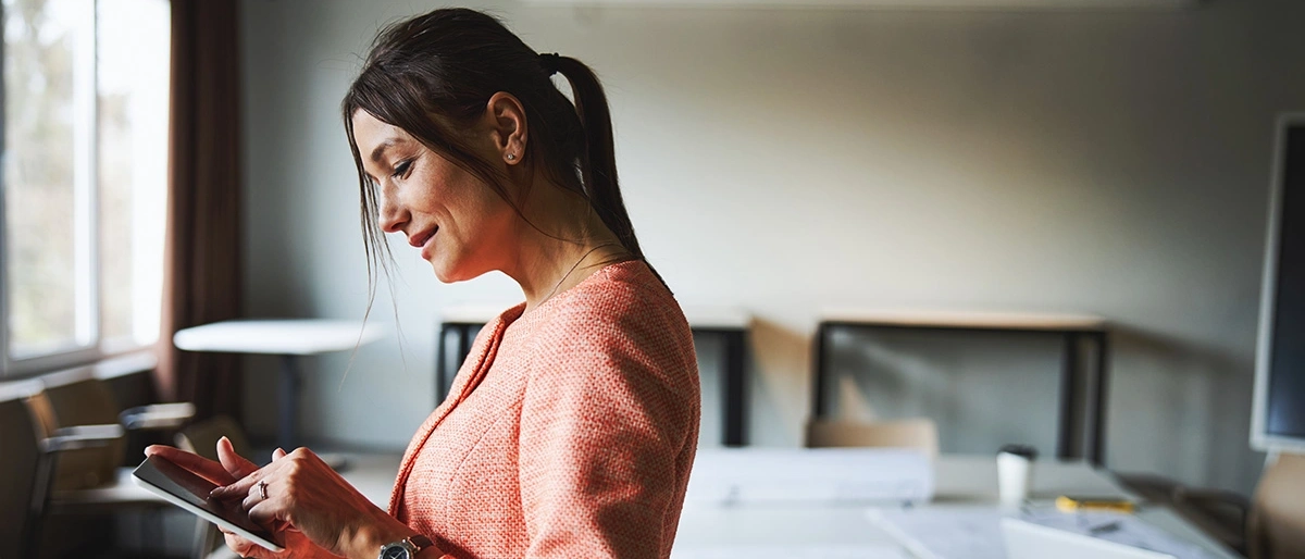 Woman looking at tablet in her hands.
