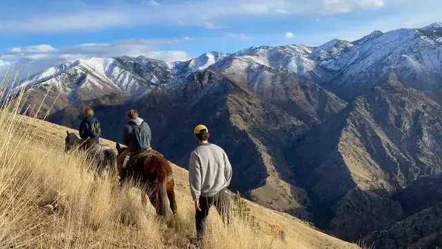 People ride horses in front of mountains