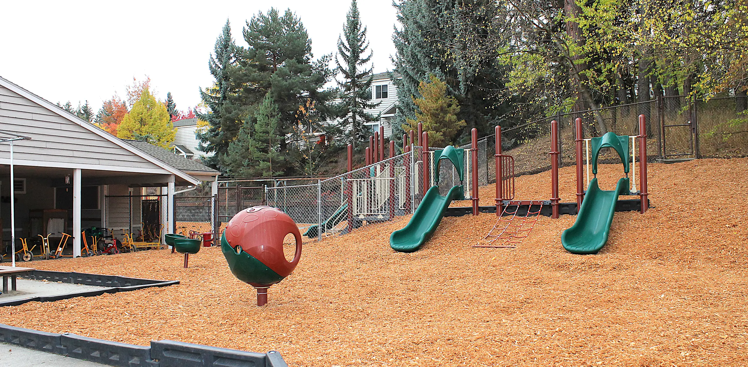 A playground with jungle gym, slides, and small outdoor toys.