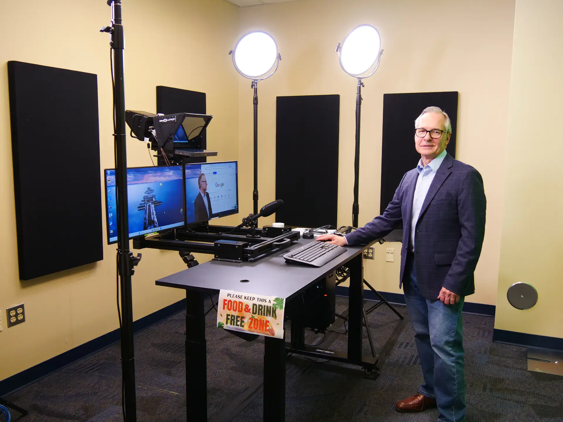 Rick Gividen, wearing blue sport coat and jeans, stands at a desk 