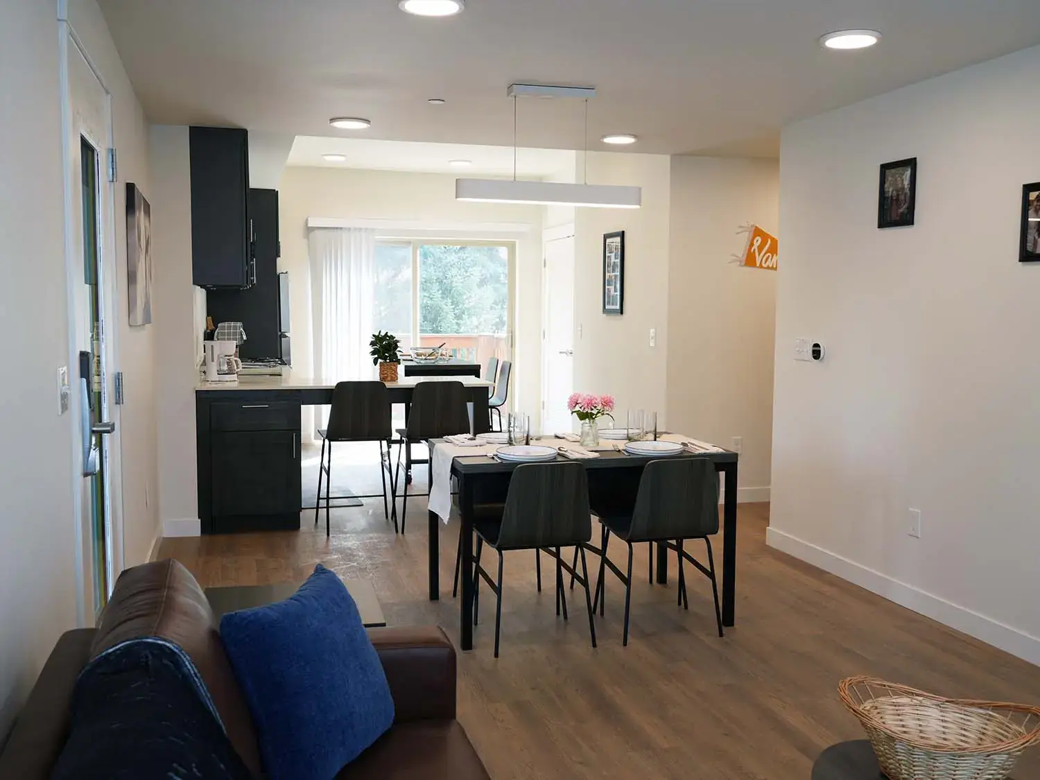 Dining area and kitchen in a Vandal Village Family Housing apartment with seating for four, modern cabinetry, and access to outdoor space.