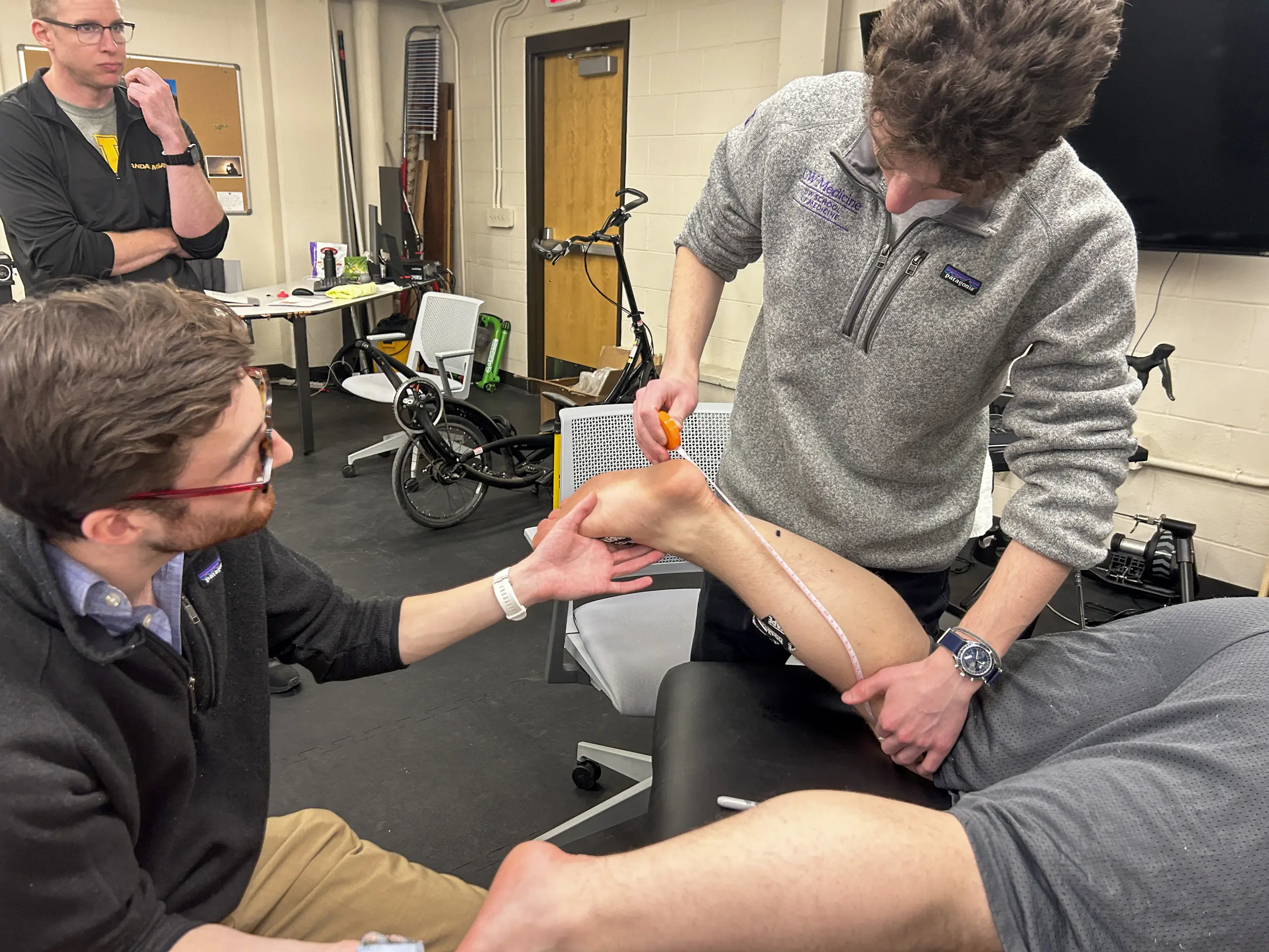 John Wadner and an assistant measure the calf of a man