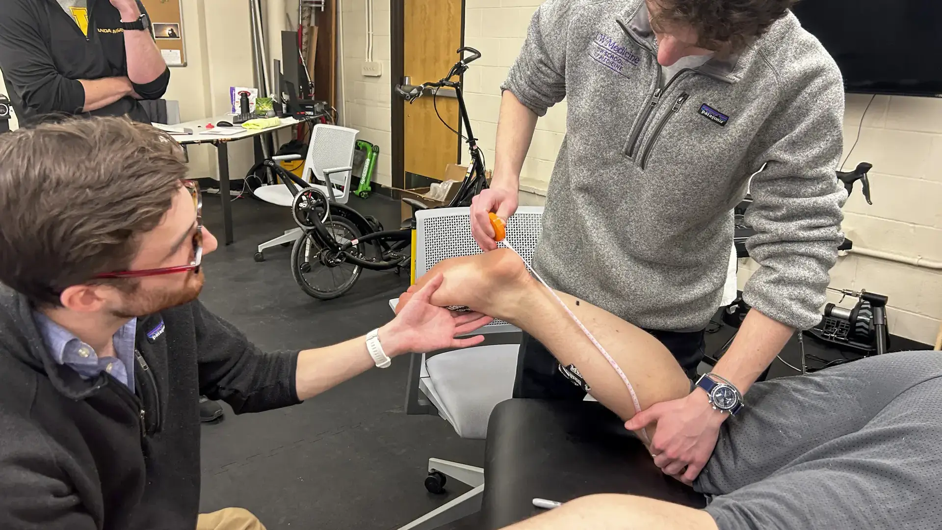 John Wadner and an assistant measure the calf of a man
