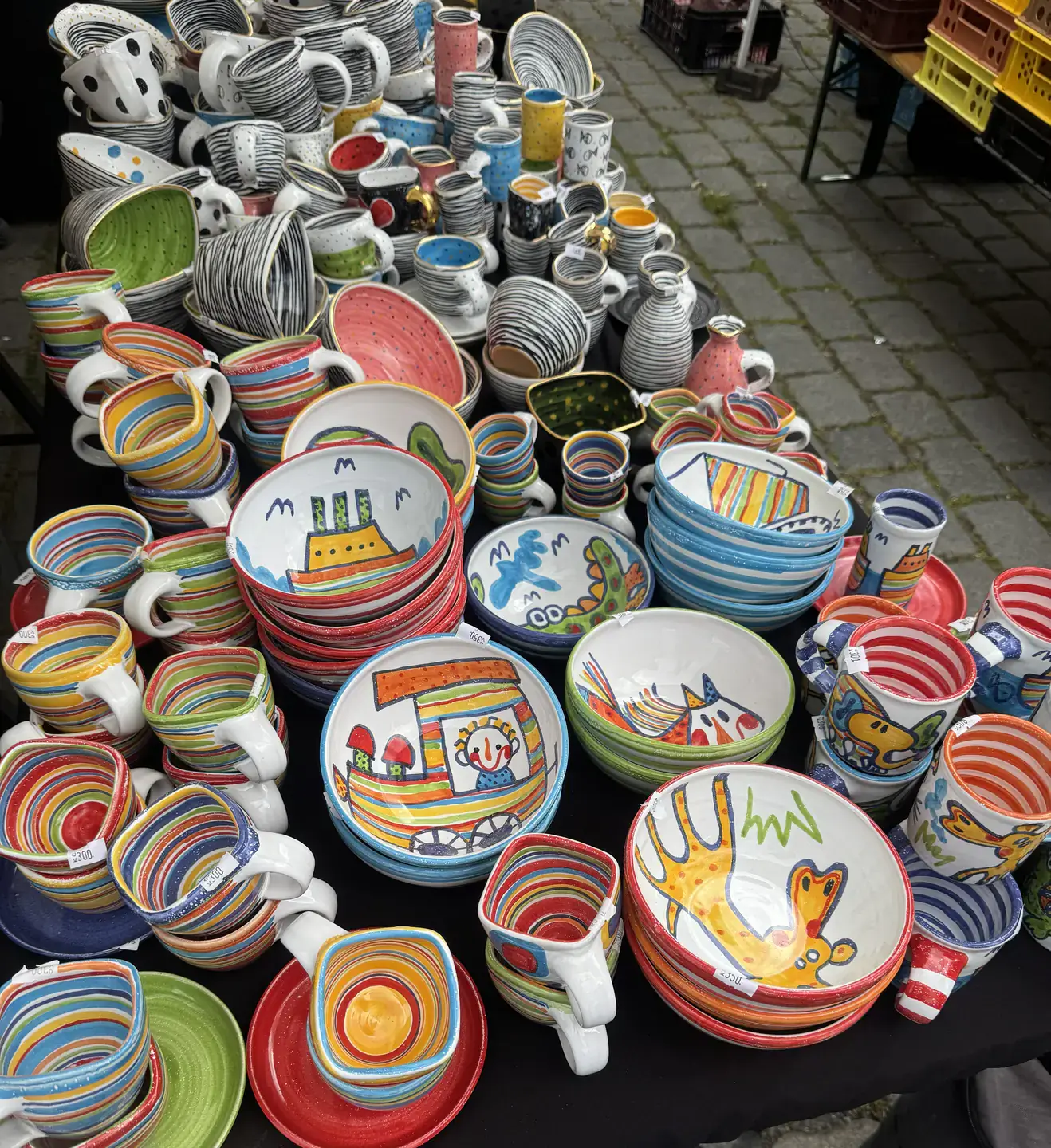 Colorful stacked cups, plates and bowls sold by a street vendor.  