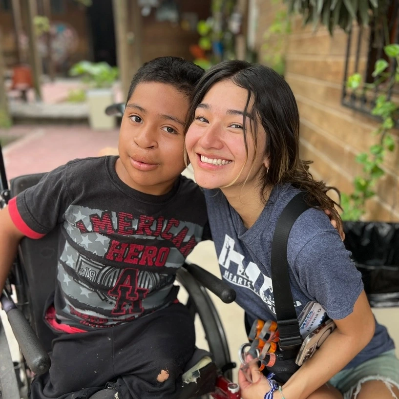 A young man in a wheelchair and woman kneeling next to him