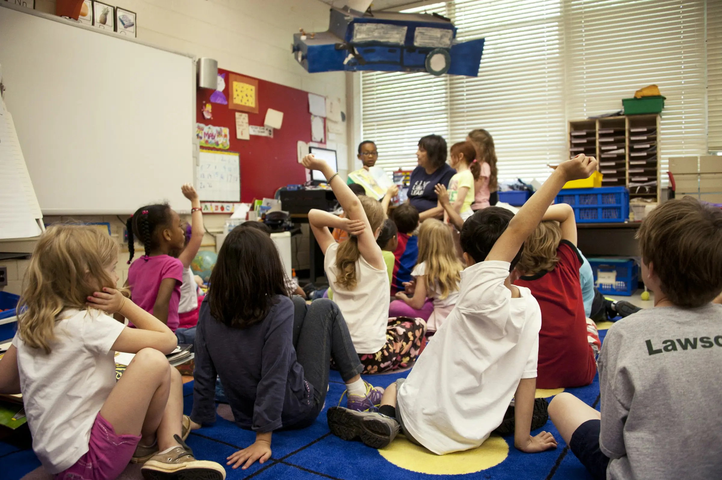  Preschoolers sit on the floor in a classroom.