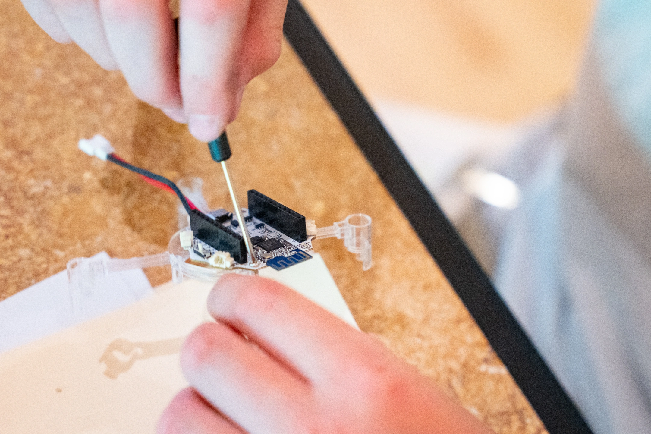 Two hands hold a small tool as they modify a drone.