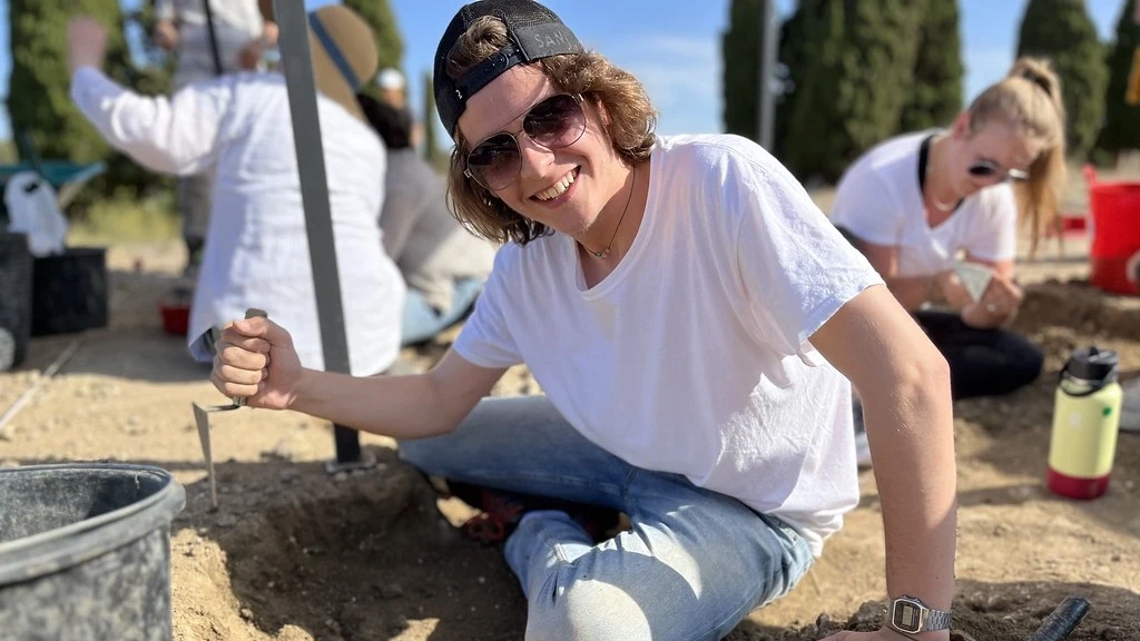 A student uses a pick at a Roman archeological site.