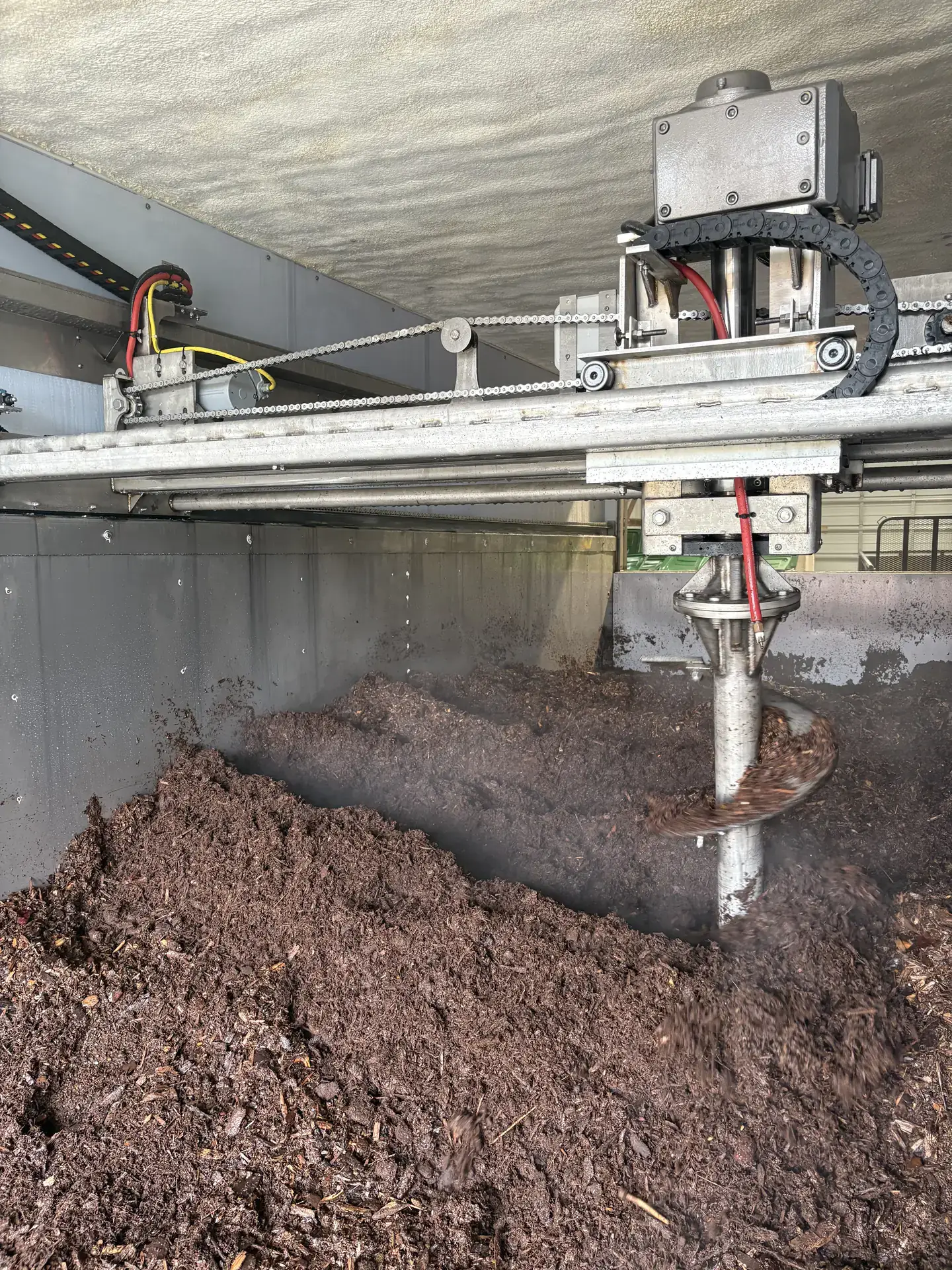 An auger turns compost inside of a storage container.