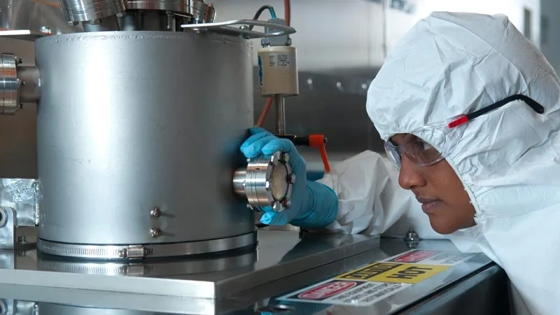 person in lab protective equipment examines device up close to get a reading