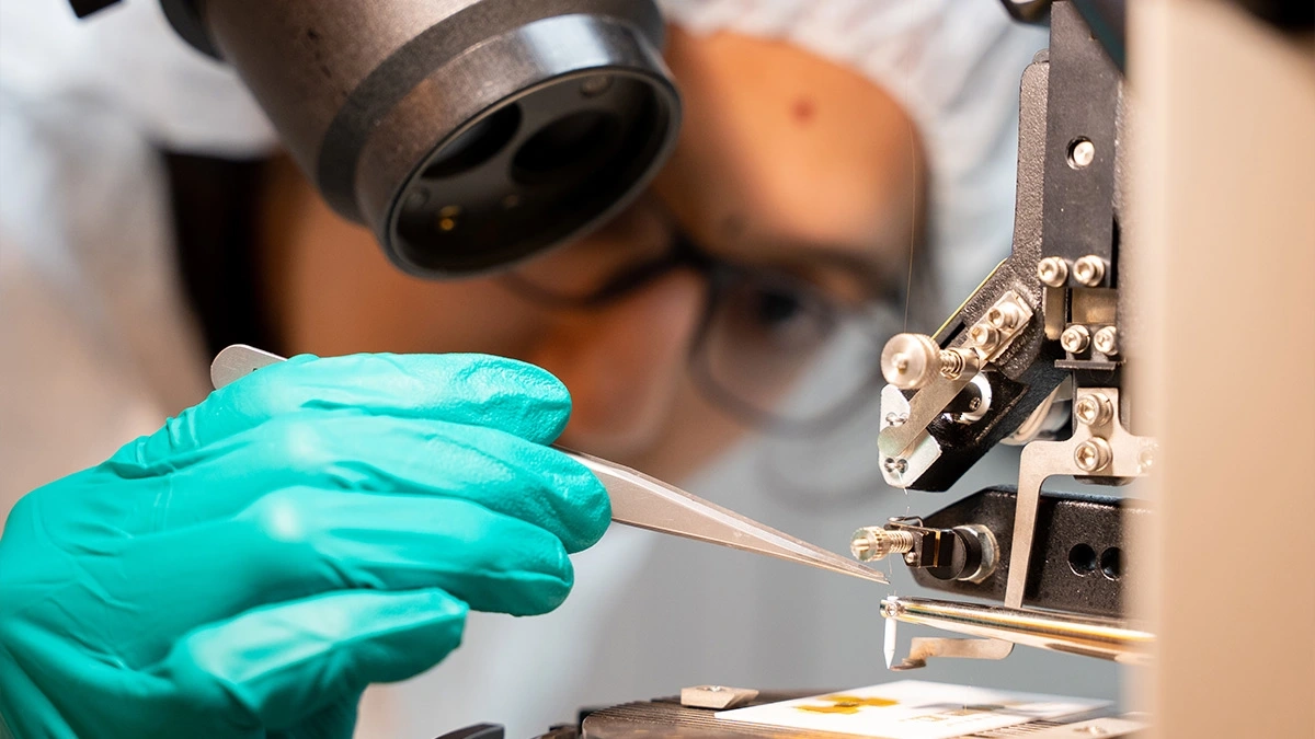 Student in lab gear using an x-ray to look at a microchip.