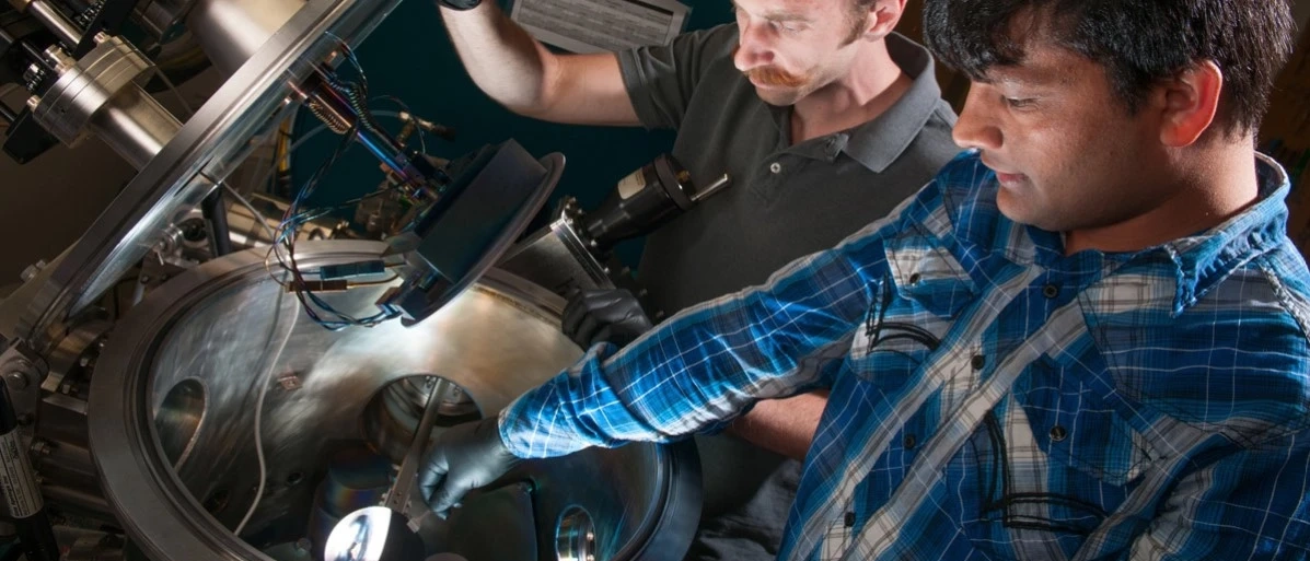 Two people wearing latex gloves work on equipment