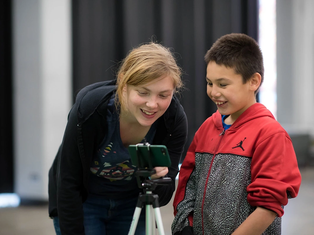 Woman and student look at a phone.