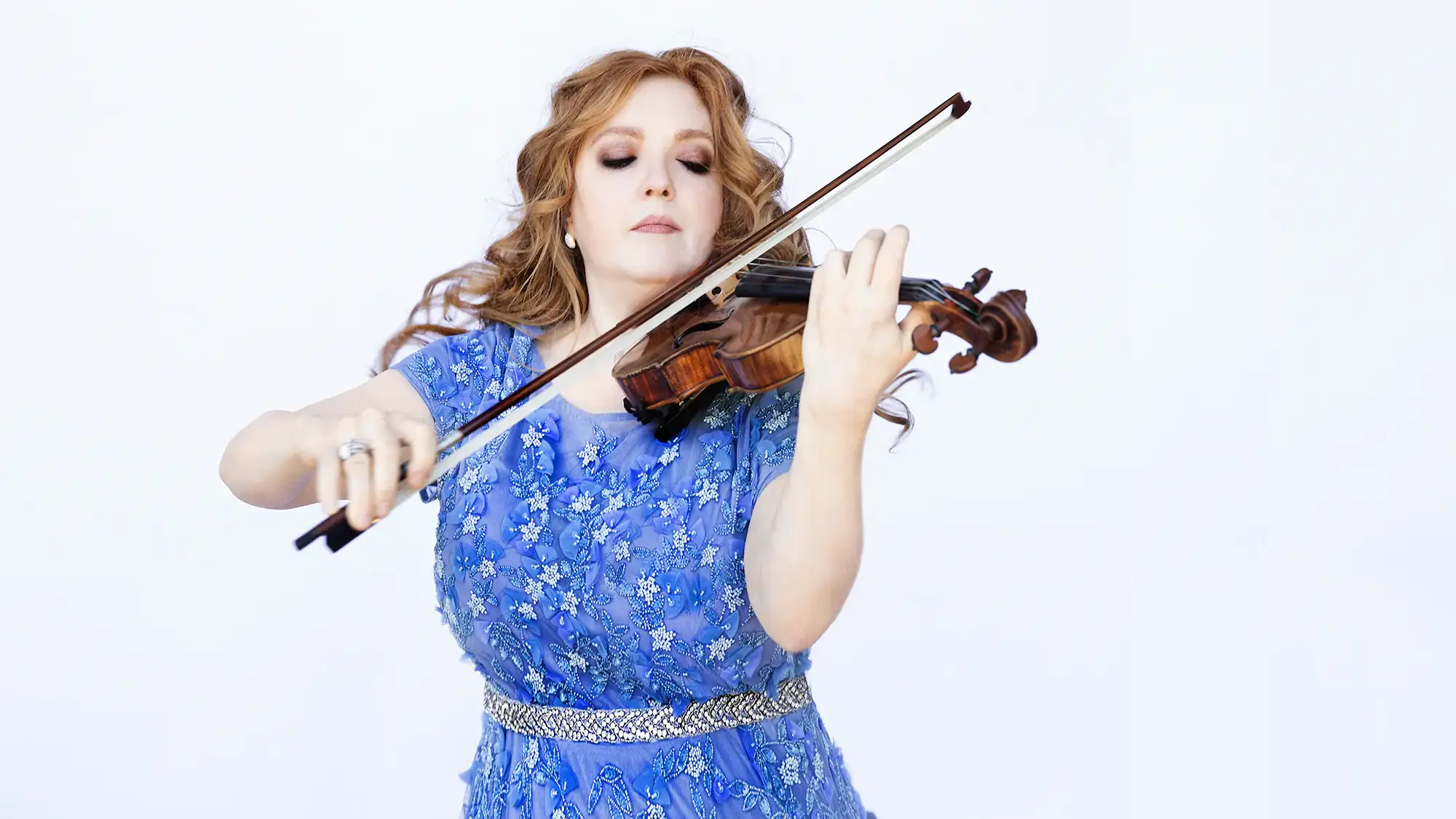  Rachel Barton Pine, wearing a blue dress, plays a violin.