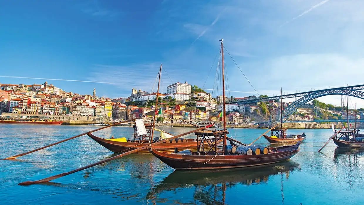 A panoramic view of a village along the Douro river behind a pair of riverboats