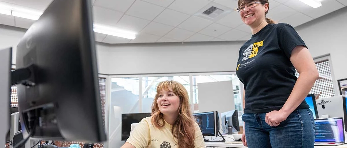 Two U of I students looking at a monitor in a computer lab. 