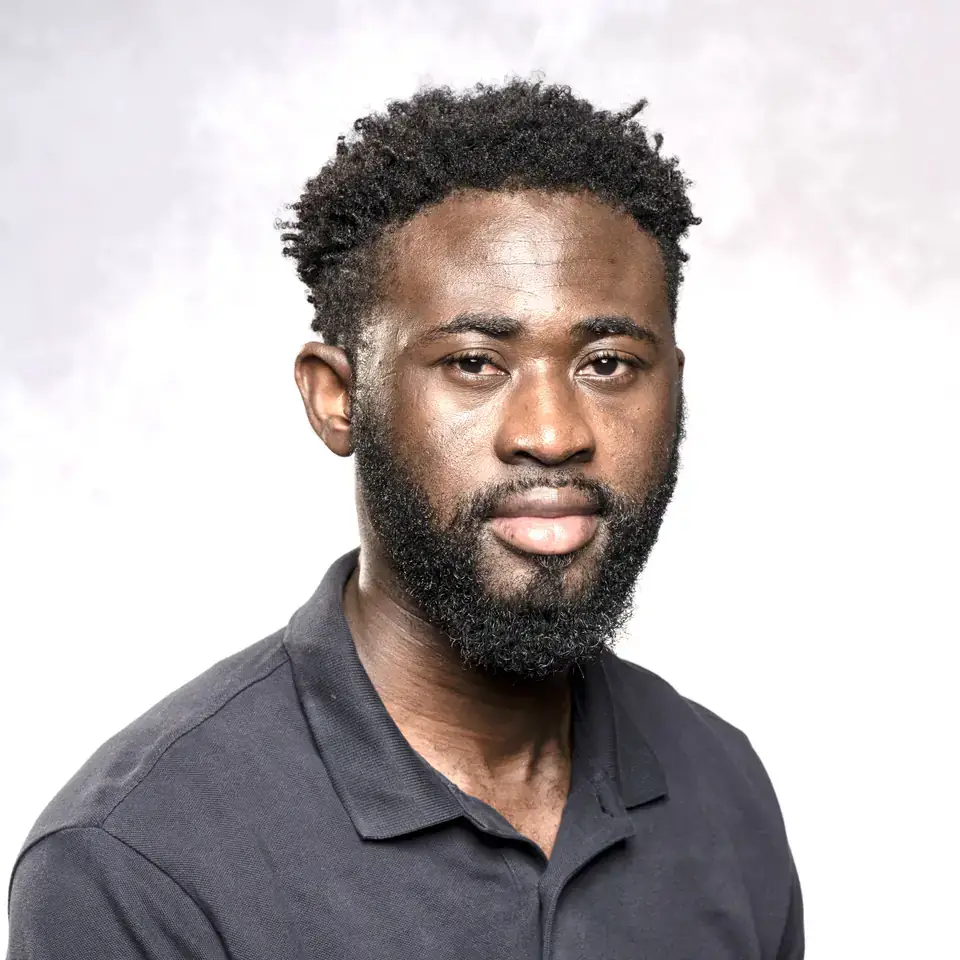 Studio portrait of a bearded man in a dark polo shirt against a light gray background