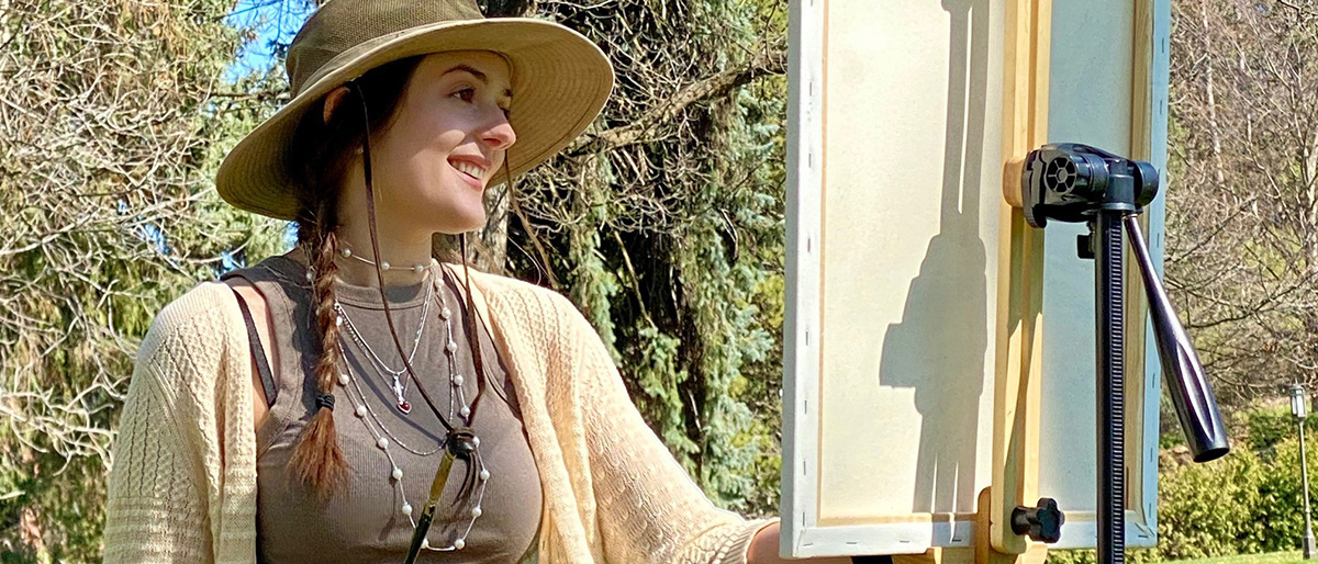 Closeup of woman painting with trees in background.
