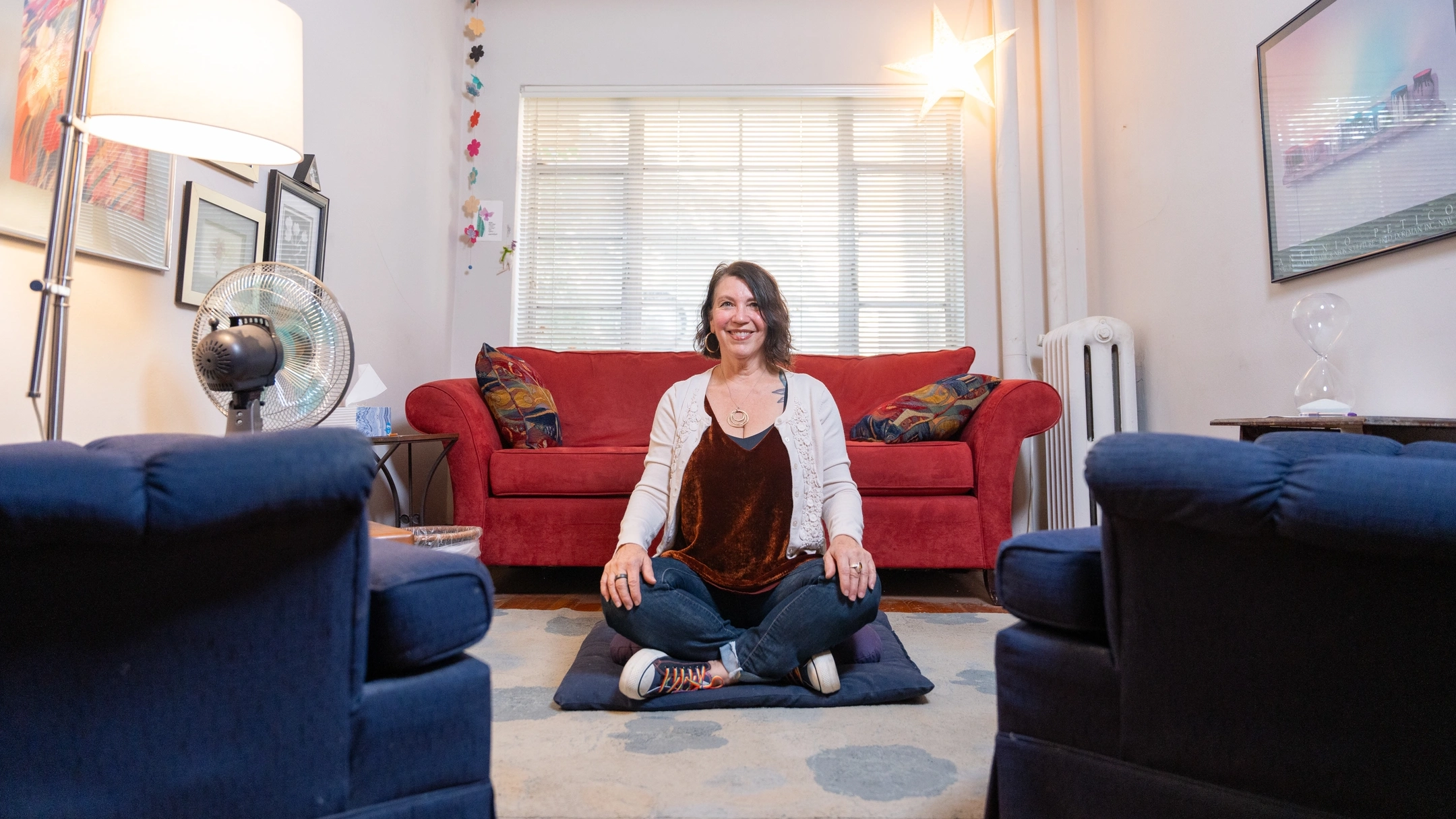 Professor Jamie Derrick sits on the floor in lotus position in her office.
