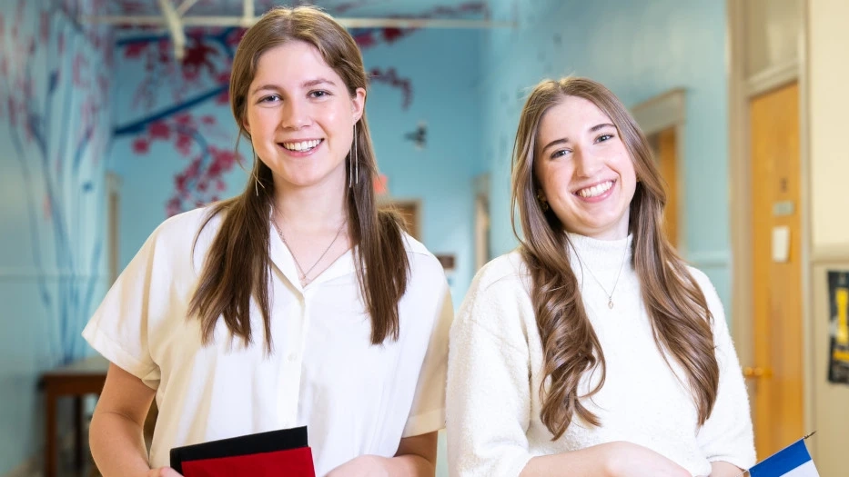 Sarah Margaret Horn and Zoë Lindner smile while holding national flags