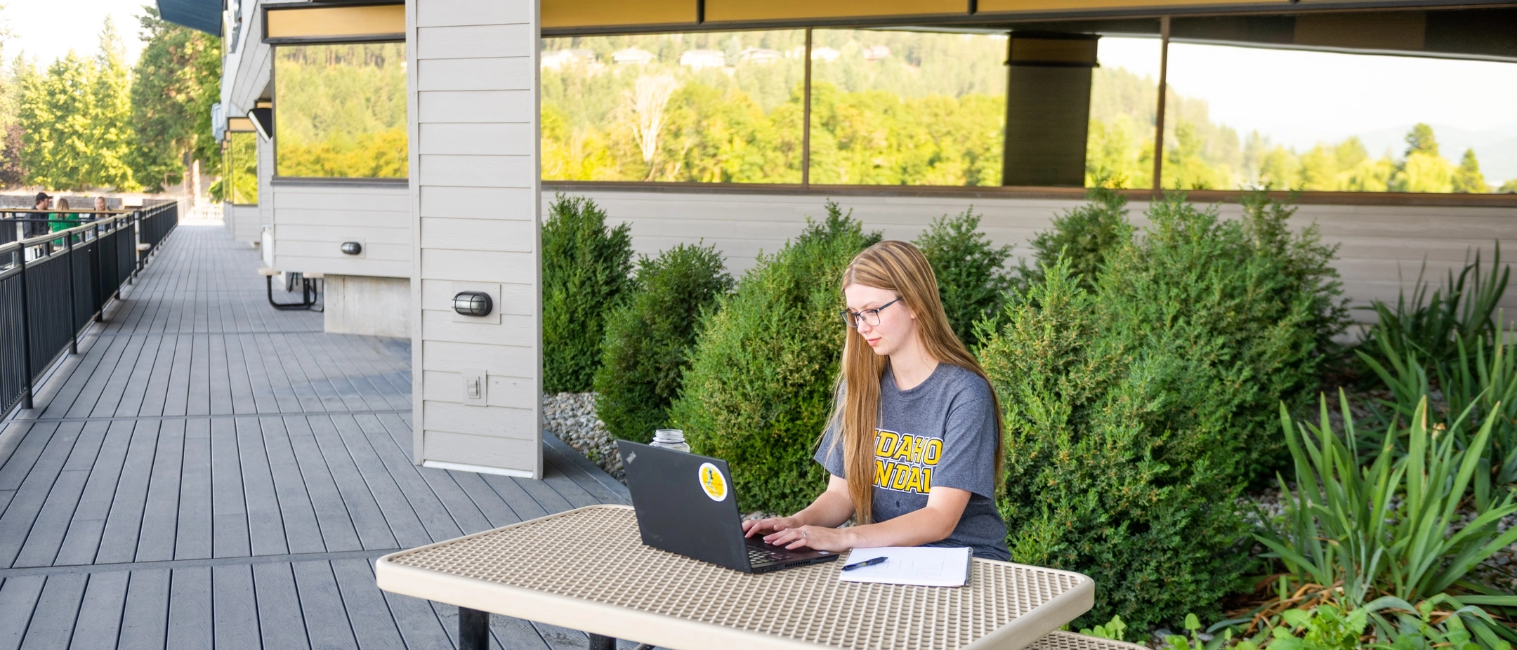 Woman at U of I Coeur DAlene Harbor Center studying outside on laptop