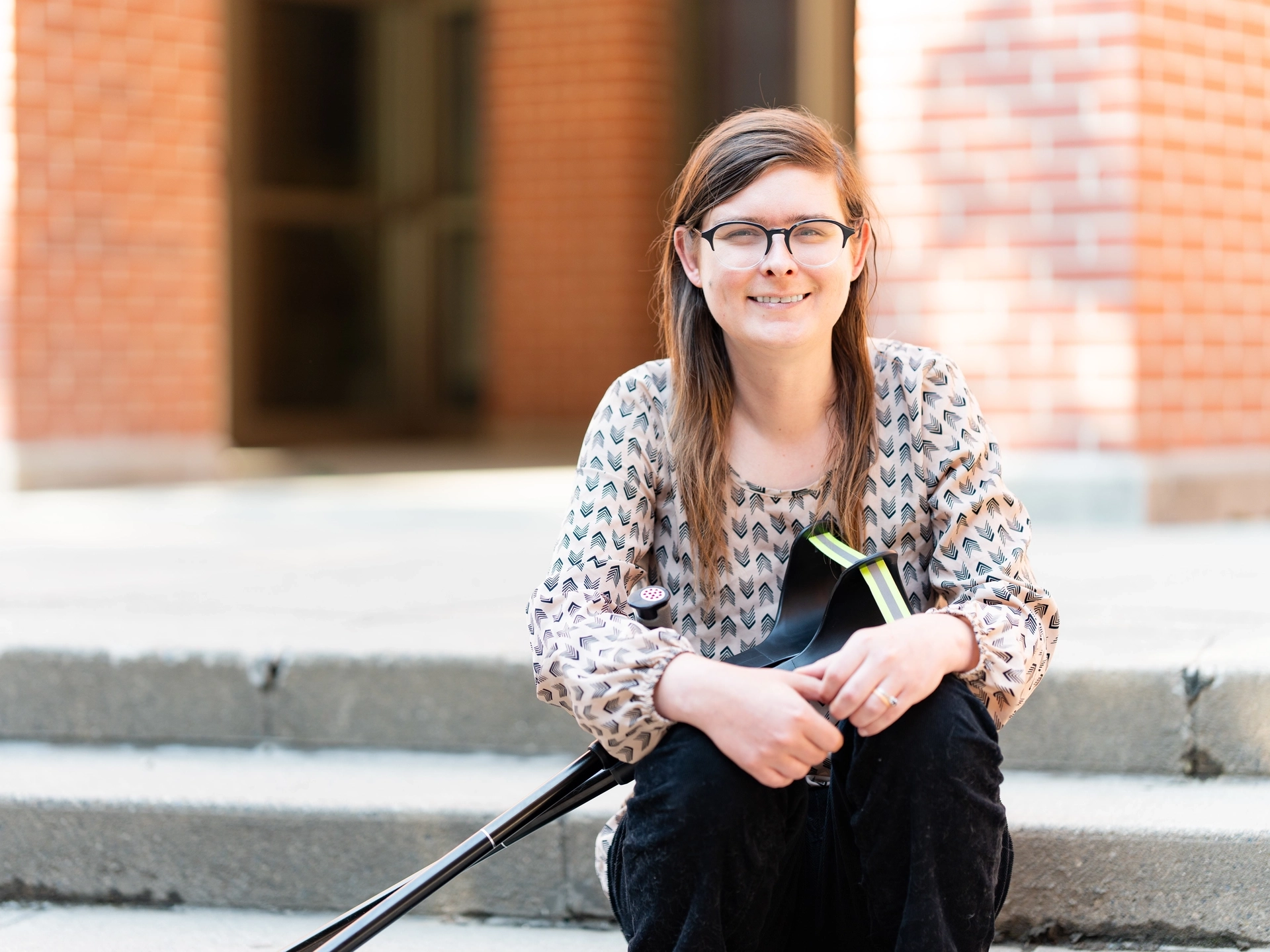 A women in glasses sitting on a step while smiling