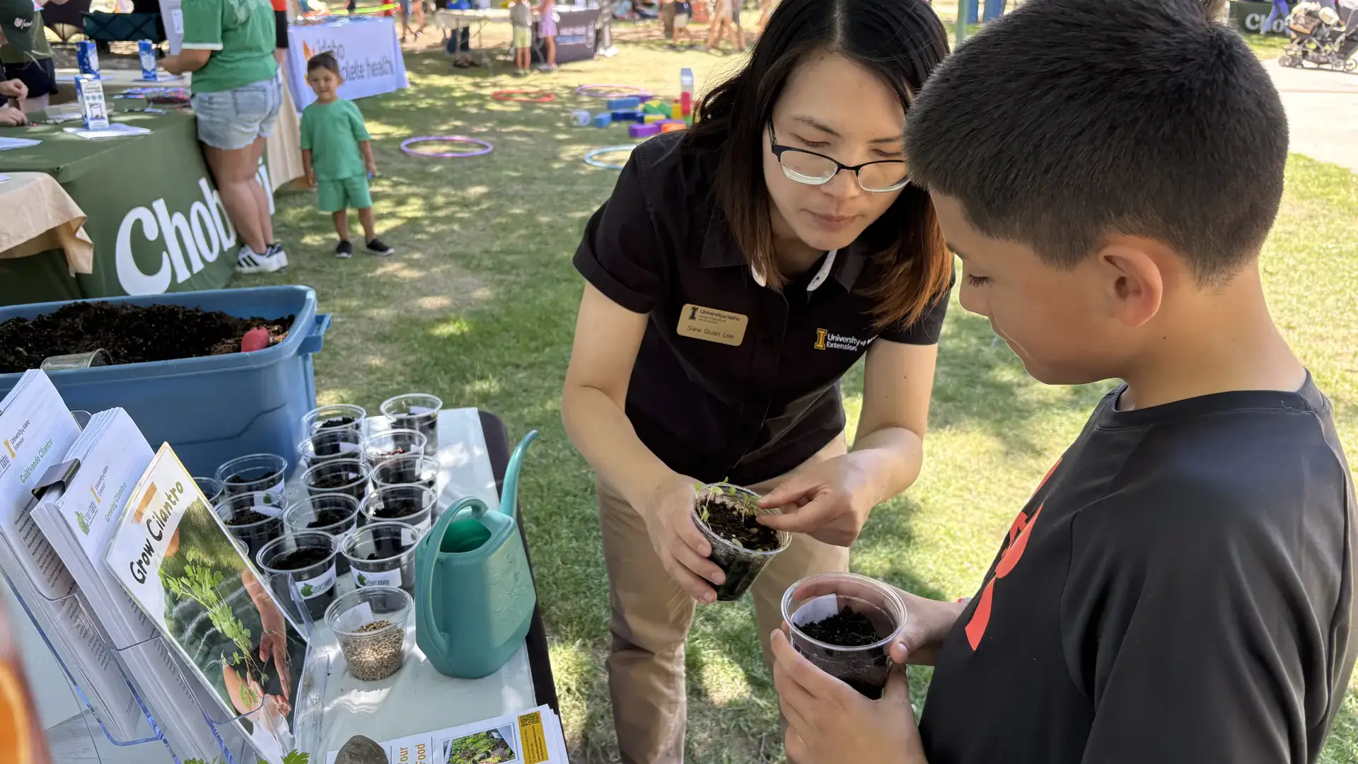 A woman shows a boy a plant growing in a cup.