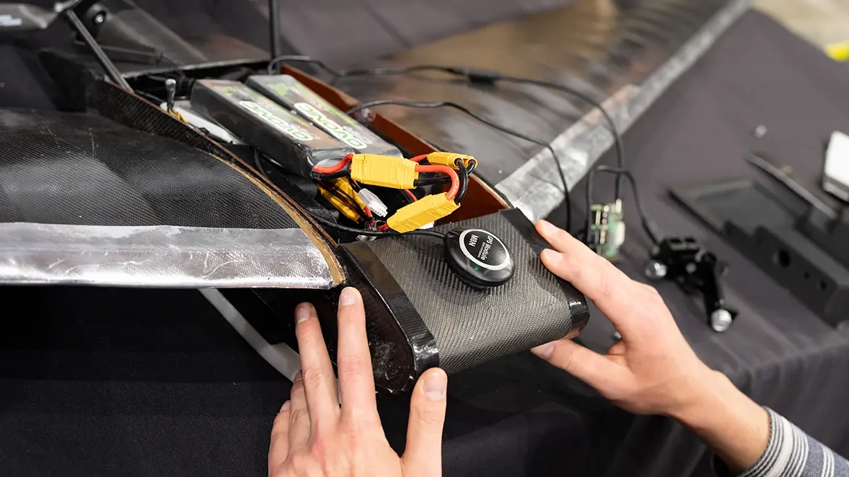A student touches the nose of an unmanned arial vehicle prototype used for wildfire detection