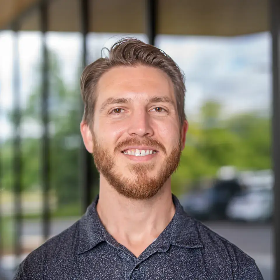 A man wearing a University of Idaho WWAMI Medical Education polo standing indoors with a windowed background.