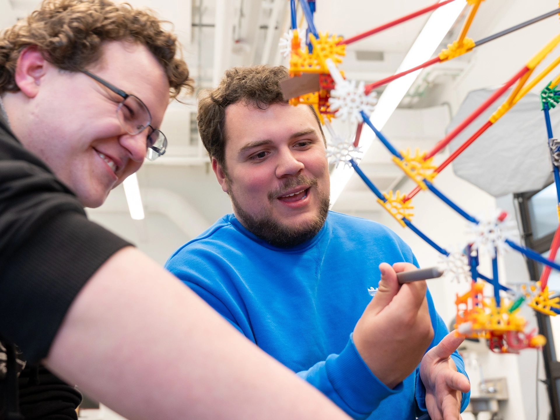 Photos of upcoming graduates in the cyber security program showing off a model ferris wheel which replicates how a cyber attack could affect mechanical processes.