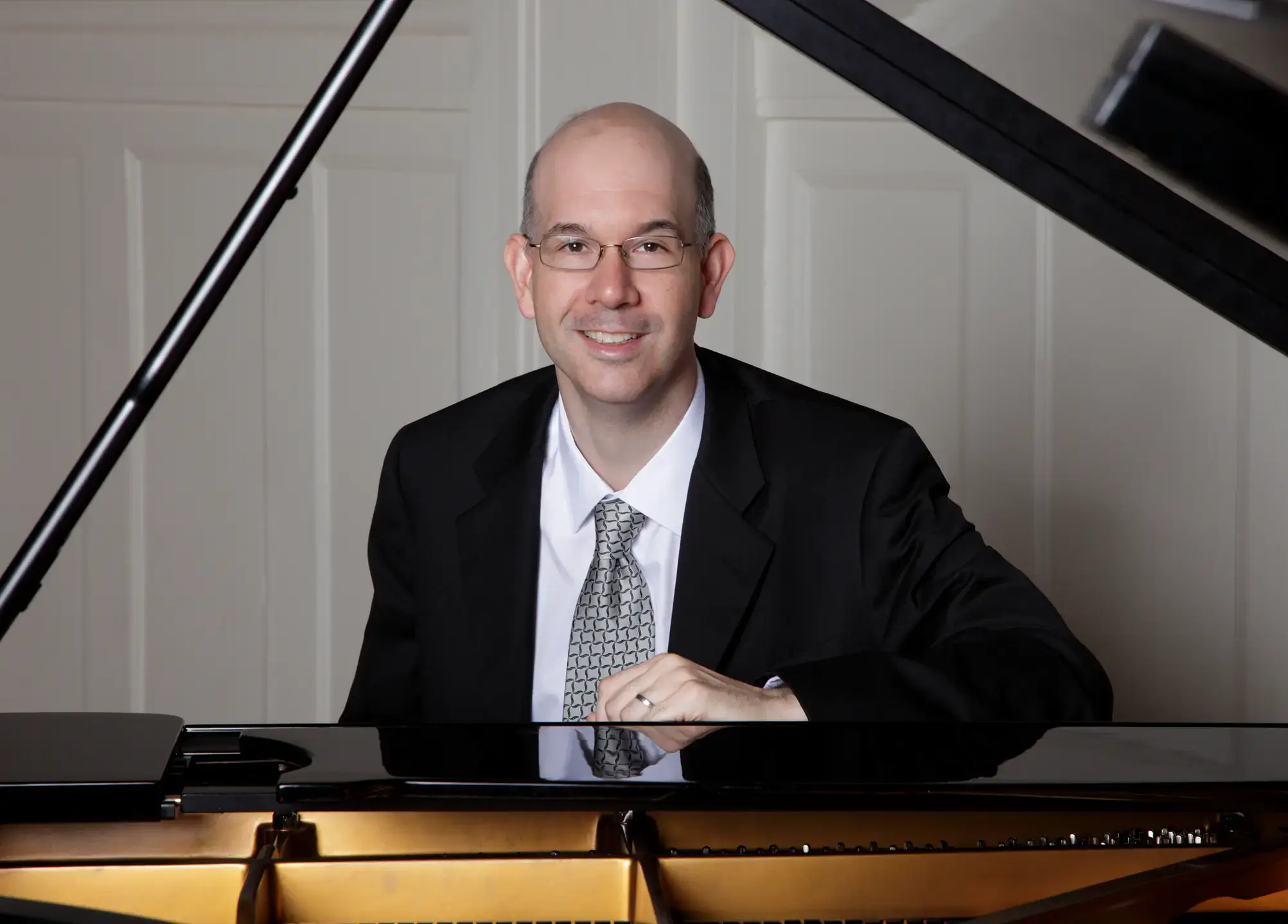 Matthew Hagle, in formal attire, sits at a piano.