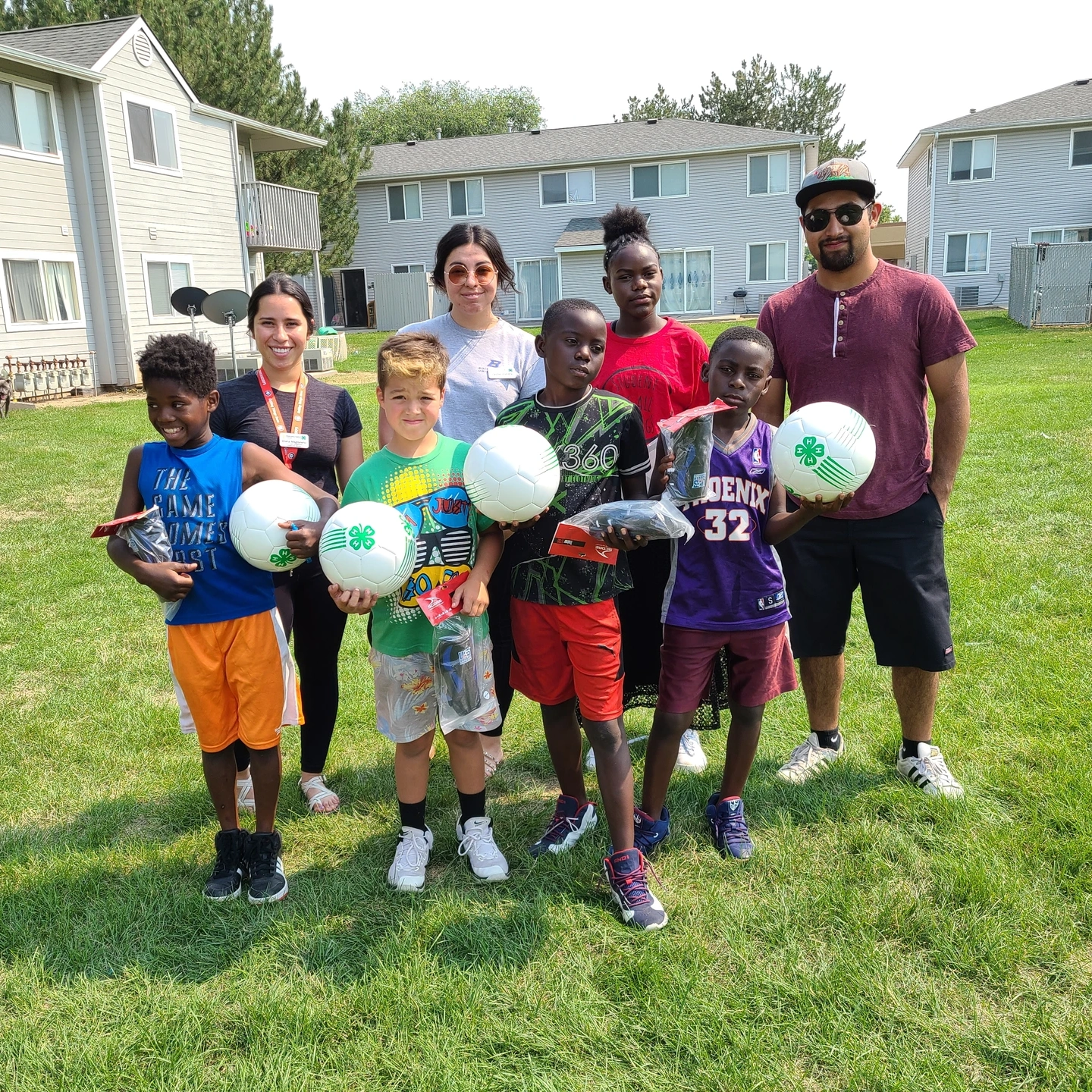 Children hold 4-H branded soccer balls.