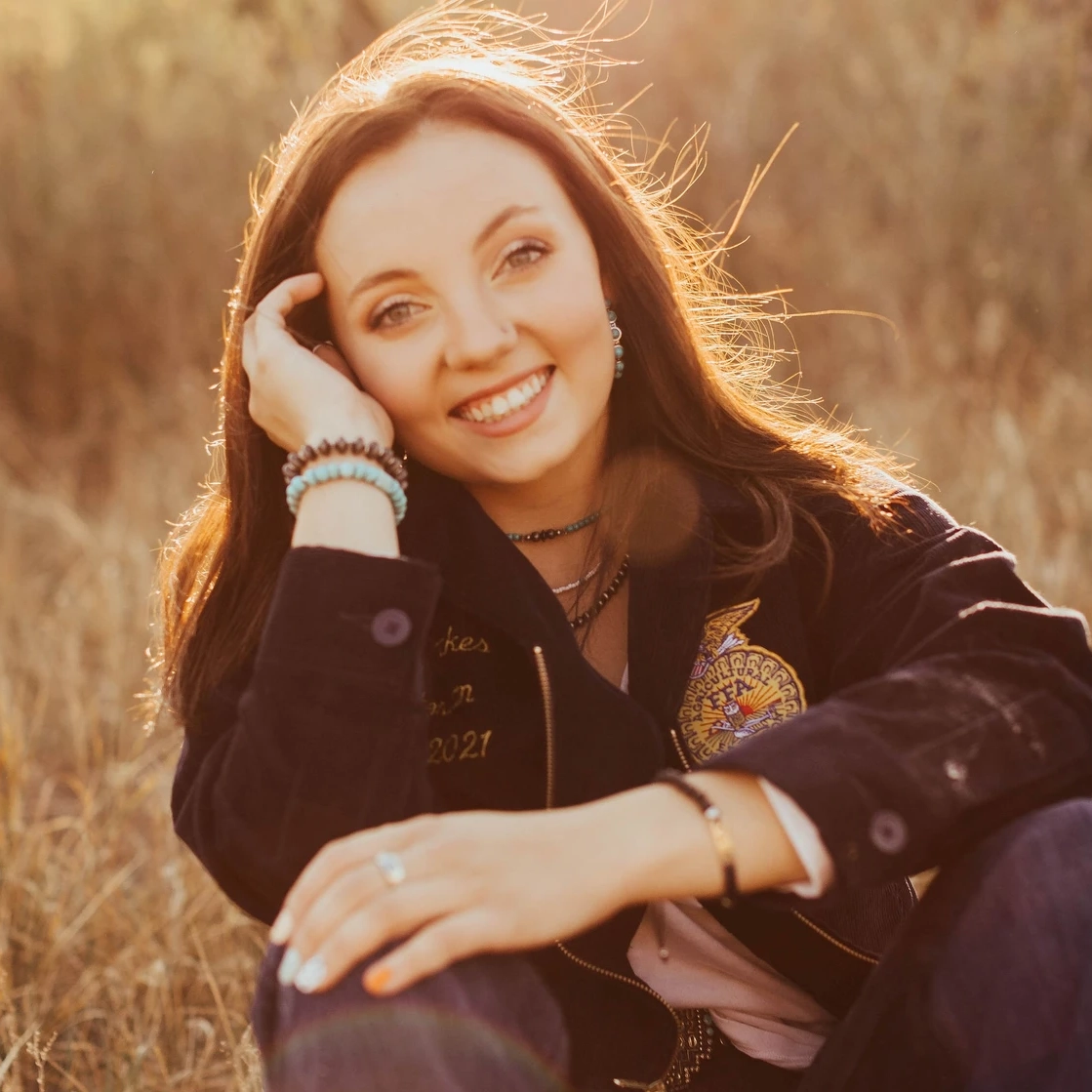 A woman sitting in a dry grass field