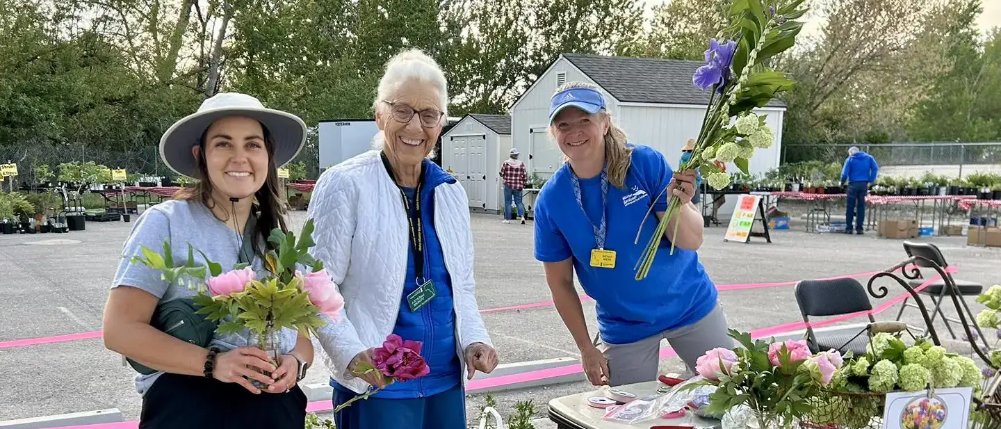 Three people holding flower cuttings