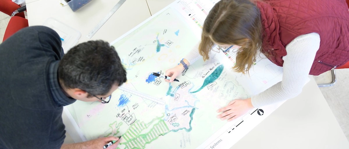 A student and faculty member work on drawing a map