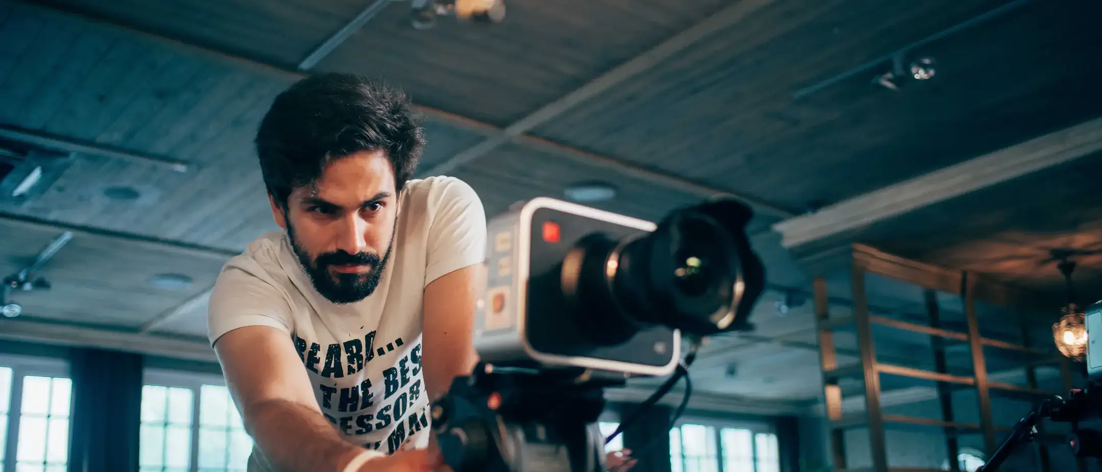 Director of photography with a camera in his hands on the set. Professional videographer at work on filming a movie, commercial or TV series. Filming process indoors, studio